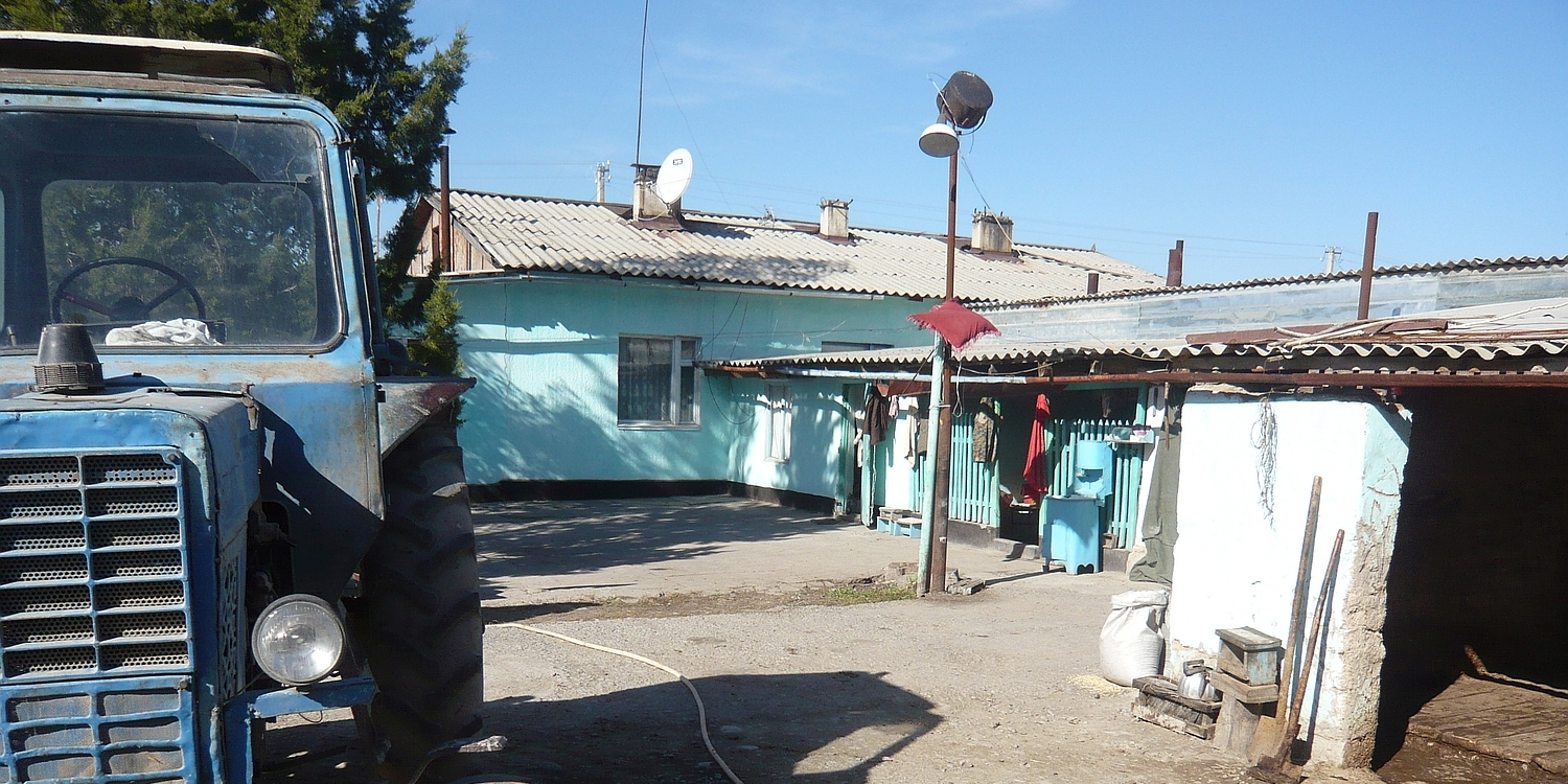 Kirgisischer Bauernhof mit Traktor und Gebäuden