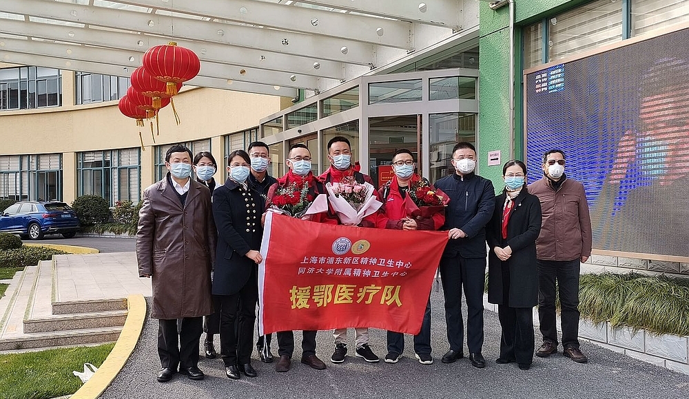Gruppe mit Gesichtsmasken und rotem Banner zur Bekämpfung des Coronavirus © Shanghai Pudong New Area Mental Health Center, China
