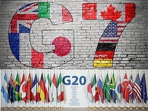 G7 Grafitto auf einer grauen Ziegelmauer und G20 flankiert von Flaggen auf einer glatten Wand