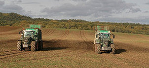 Traktoren bringen Teststoffe (in iesem Fall Hackschnitzel) auf einem Feld auf.